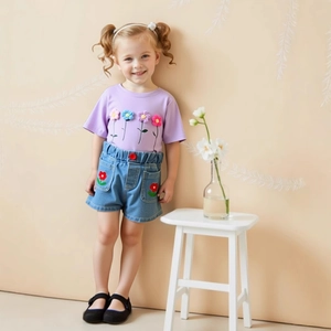 Close-up of a girl's purple T-shirt with 3D floral crochet and denim ruffle shorts