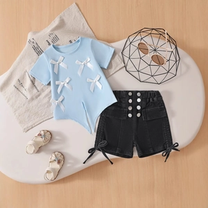 Detailed flat lay of blue bow-knot tee and denim shorts set with metal buttons
