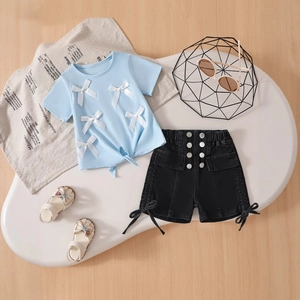 Flat lay of kids summer set with light blue bow t-shirt and denim shorts with buttons