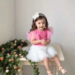 Detail of girls' summer outfit featuring pink ribbed top with tulle ruffles and white tiered skirt
