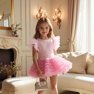 Detail of pink knit top with ruffled sleeves and tiered tulle tutu skirt on girl model