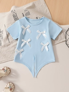 Flat lay of light blue girls t-shirt featuring five white satin bows and a pointed hem