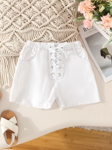 Detail of white denim shorts featuring elastic waist, drawstring eyelets and raw hem edges