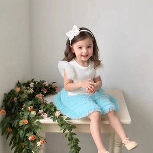 Detail of white knit top with ruffled mesh sleeves and layered blue tutu skirt