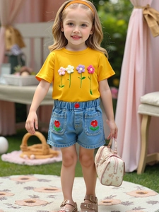 Girls summer casual set with yellow floral t-shirt and denim shorts in garden picnic scene