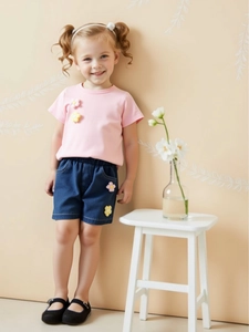 Girls summer set with pink floral t-shirt and dark blue denim shorts in warm studio