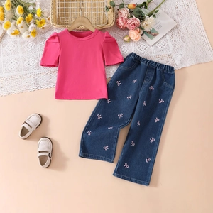 Flat lay detail of girl's pink puff sleeve shirt and denim pants with bow embroidery