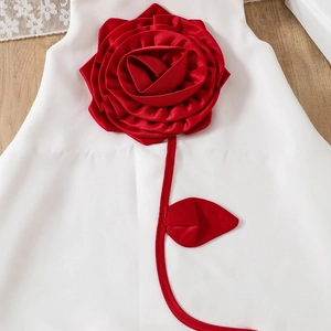 Gros plan d'une robe de fête blanche ornée d'une grande rose rouge en satin 3D