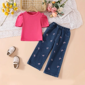 Detail of girls' puff sleeve top and jeans with pink bow embroidery and elastic waist