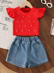 Detail of red ruffle sleeve top with pearls and denim shorts on wooden background