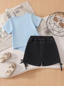 Summer kids set with light blue bow t-shirt and black denim shorts on wooden background