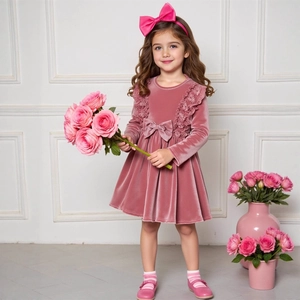 Detail eines rosa Samtkleids für Mädchen mit Spitzenrüschen und großer Zierschleife