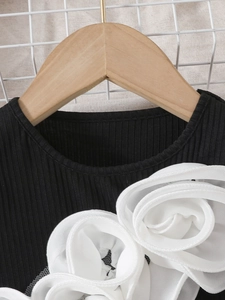 Detail of black ribbed knit top featuring large 3D white chiffon floral appliqués