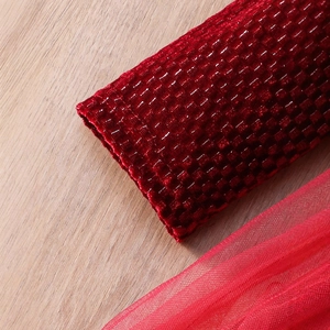 Dettaglio dell'abito in velluto rosso con tessuto testurizzato e polsino in tulle