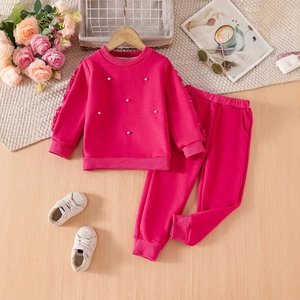 Flat lay of a girls pink beaded sweatshirt and jogger pants set with trendy accessories