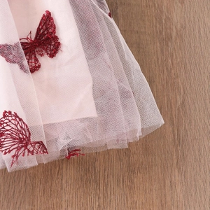 Detailansicht von rosa Netzstoff mit aufwendiger dunkelroter Schmetterlingsstickerei
