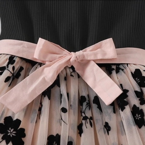 Detail of pink bow belt with black floral mesh embroidery on the waist of a girl's dress