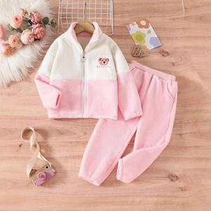 Detailansicht eines rosa Fleece-Trainingsanzugs mit Bärenstickerei auf Holzhintergrund