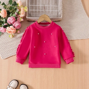 Detail of rose pink girls sweatshirt featuring white pearl beads and ruffled sleeve accents