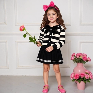 Detail of girls' striped knit cardigan with bow and black pleated skirt in school style