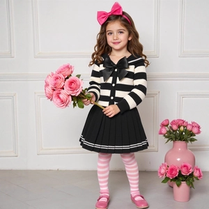 Detail of girl's knit cardigan with black bow and matching pleated skirt outfit