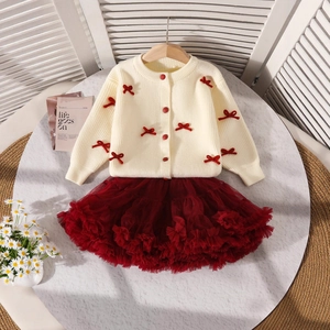 Détail du cardigan en maille crème avec nœuds rouges et jupe tutu bordeaux pour fille