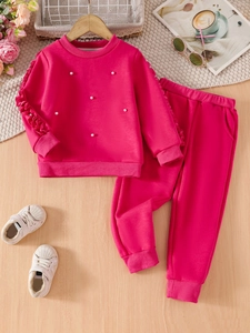 Girls bright pink sweatshirt set with pearl accents and matching joggers on wood floor