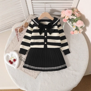 Detail of girl's knit cardigan with navy collar and pleated skirt in preppy style
