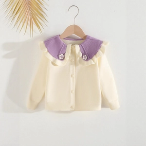 Close-up of cream knit cardigan featuring a purple ruffled collar and white floral details