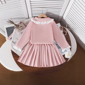 Detail of pink girls outfit with white lace ruffles and pleated skirt on a hanger