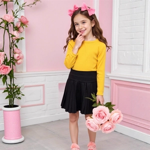 Detail of girls' yellow ribbed long sleeve top and black pleated skirt with subtle sparkles