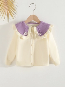 Girls beige knit cardigan with purple ruffle collar and floral detail on wood hanger
