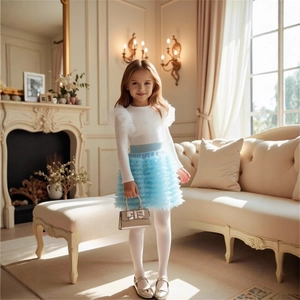 Detail of girls' long sleeve white knit top and layered light blue tulle tutu skirt