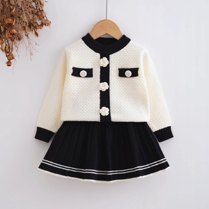 Detail of waffle knit cardigan with floral buttons and matching black pleated skirt