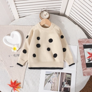 Détail du pull en tricot enfant crème à pois noirs avec poignets côtelés en gros plan