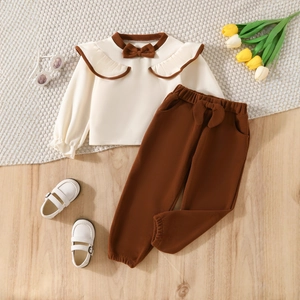 Flat lay of girls' beige long sleeve top with ruffles and brown pants set