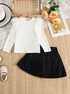 Flat lay of girl's white ribbed long sleeve top and black pleated skirt with decor