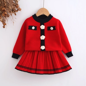 Detailed macro view of red knit cardigan with 3D floral buttons and matching pleated skirt
