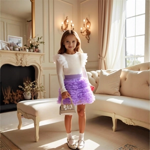 Detail of girl's white knit top with polka dot mesh sleeves and purple layered tutu skirt