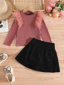 Detailed flat lay of pink knit top with ruffled shoulders and black glitter pleated skirt