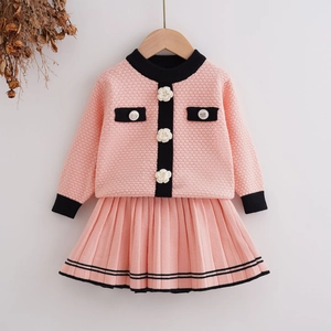 Detail of pink knit set with camellia buttons and elegant black contrast trim