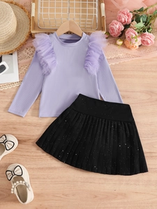 Flat lay of girl's purple ruffle top and black pleated skirt with glitter and cream shoes
