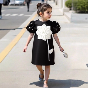 Detail of elegant black girl's dress with a 3D white rose and pearl puff sleeves