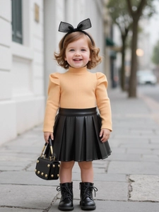 Tenue élégante pour fille avec haut en tricot orange et jupe plissée noire en cuir PU