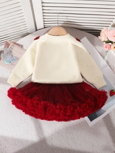 Ensemble hiver fille avec pull en tricot beige et jupe tutu rouge sur fond blanc