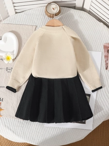 Ensemble haut en tricot beige et jupe plissée noire pour filles sur table blanche