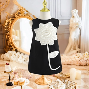 Detail of girls sleeveless black party dress with large 3D white flower appliqué