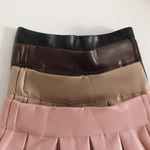 Détail de quatre jupes plissées en similicuir avec large taille en noir, marron, beige et rose
