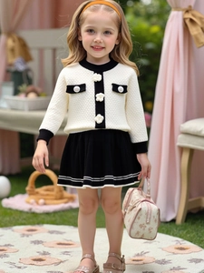 Girls two-piece knit set featuring cream sweater with 3D floral accents and black pleated skirt