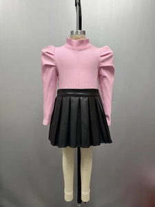 Détail du haut rose à col roulé côtelé avec manches bouffantes et jupe plissée en PU noir